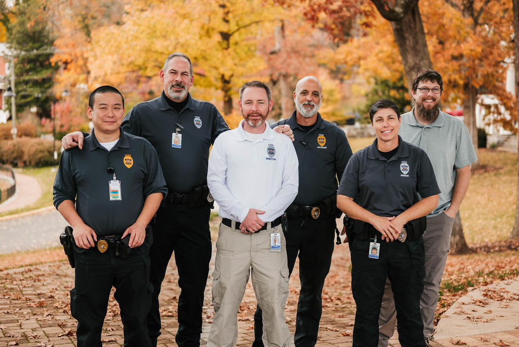 Photo of six public safety staff standing outside among yellow fall foliage 