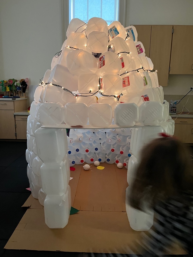 igloo made out of empty plastic milk and water jugs, lights strung around and lit