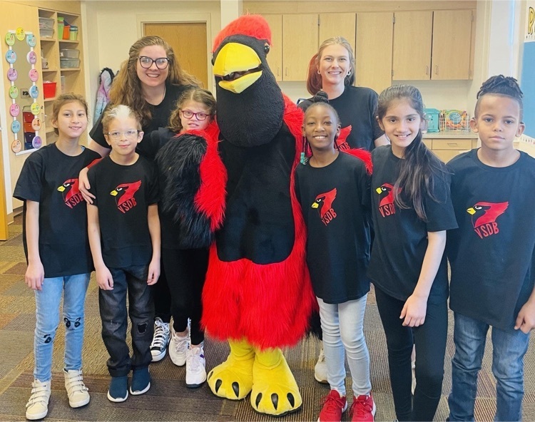 elementary students wearing black T-shirts with a cardinal logo posing for a picture with the cardinal mascot 