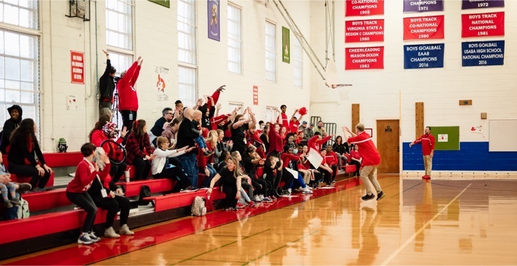 a student runs in front of the crowd sitting on the bleachers to lead the human wave
