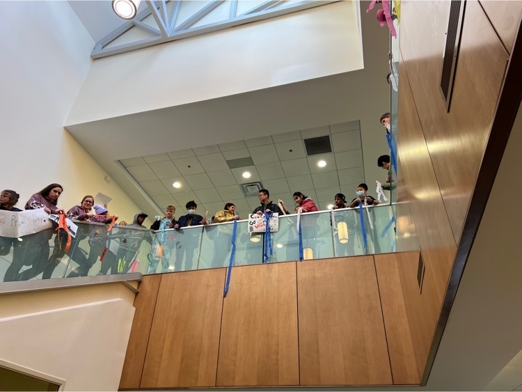 students lining the upstairs balcony and holding banners and streamers in support of the principal 