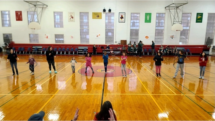 students and visitors lined up on the basketball court cheering