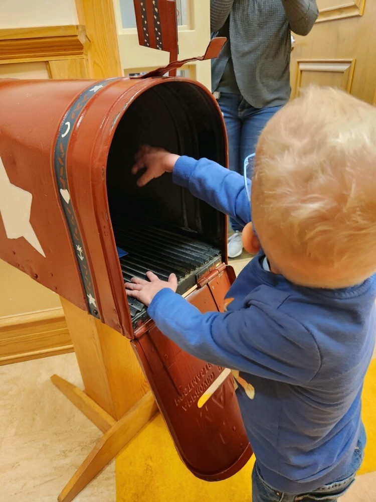 pre-K student reaching into a large mailbox