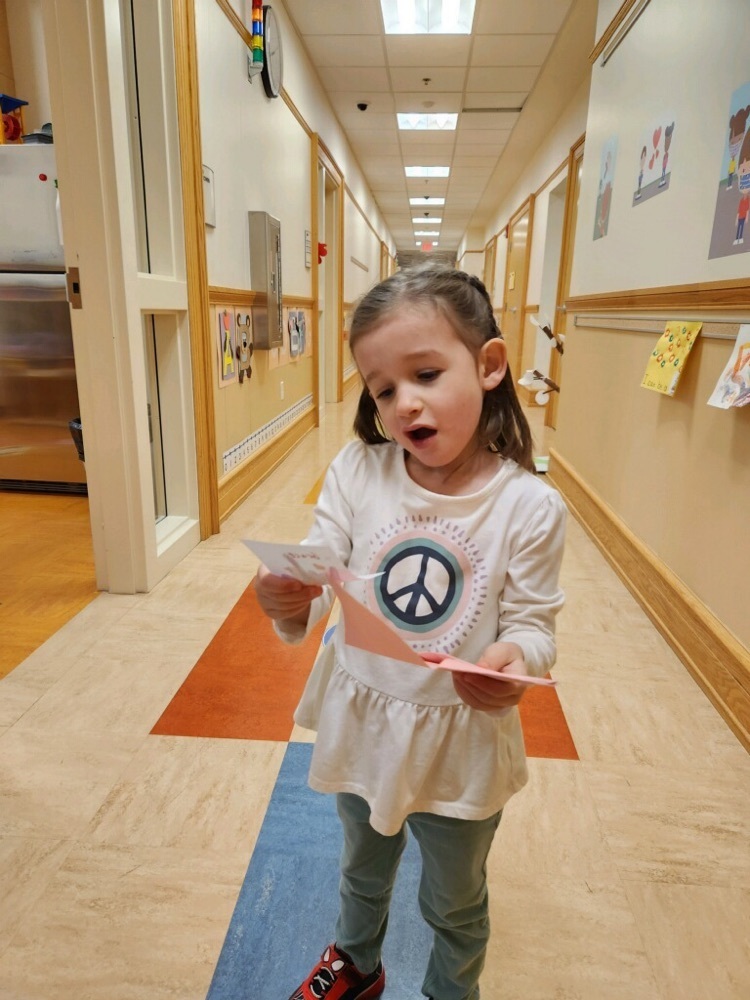 pre-K student standing in a hallway and taking a card from an envelope