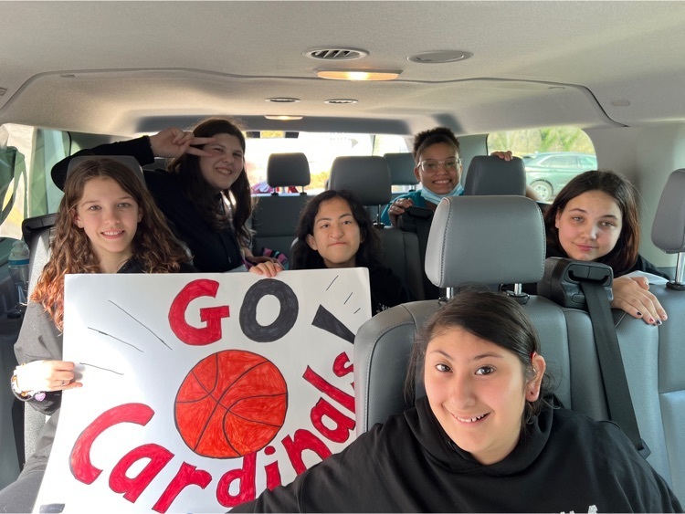 girls basketball team in the van holding a sign “go cardinals"