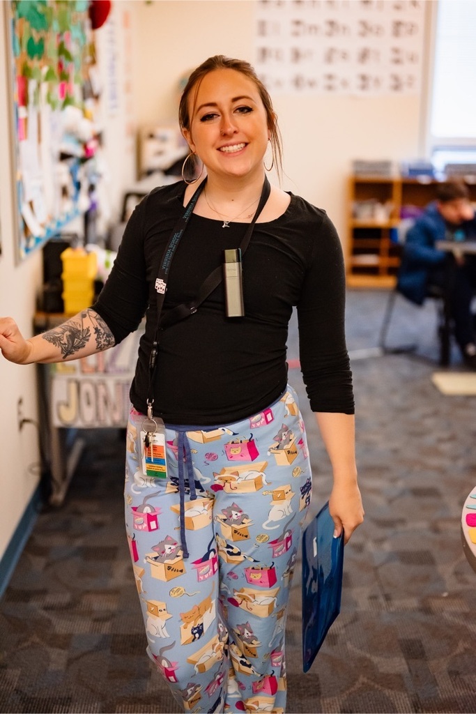 a female teacher smiles from her doorway while wearing pajamas