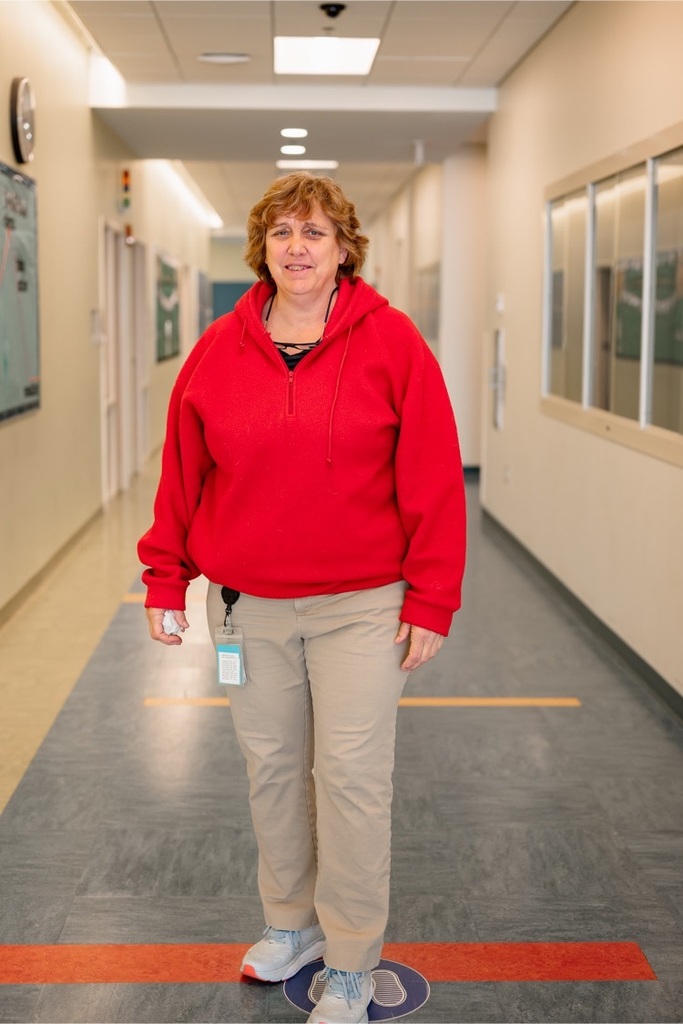 female staff wearing a red shirt standing in a hallway