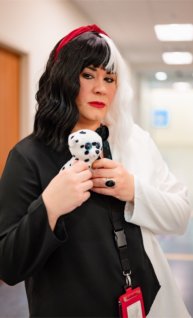 female staff dressed as cruella de’vil and holding a toy Dalmation 