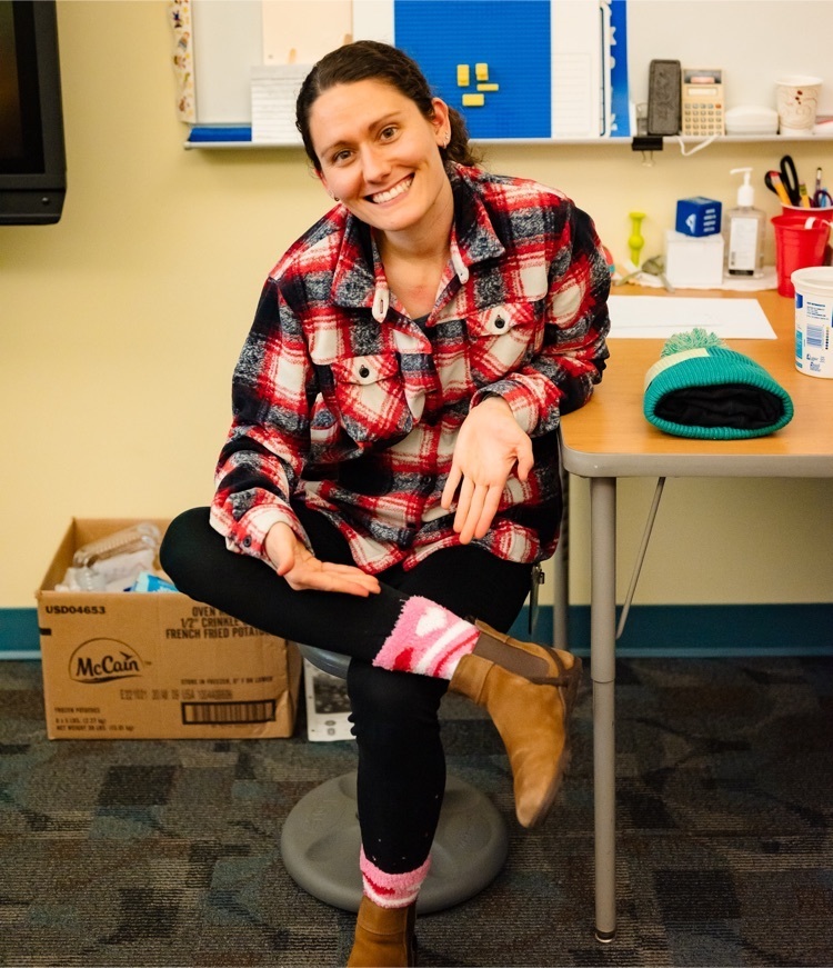 female staff sitting at a desk points to her fuzzy socks