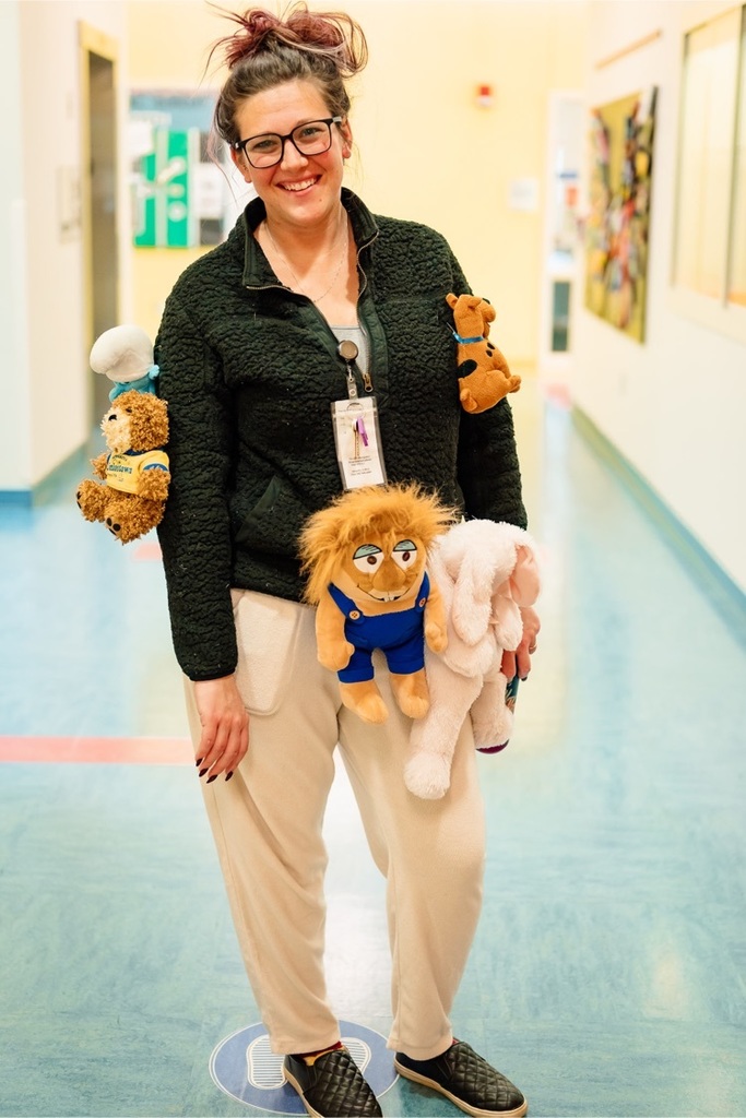 female staff member wearing fuzzy clothes with fuzzy stuffed animals pinned to them