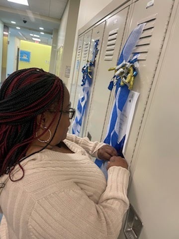 female staff arranging blue and white streamers on a locker