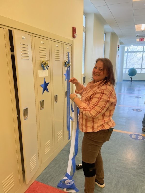 One staff smiles as she decorates a locker
