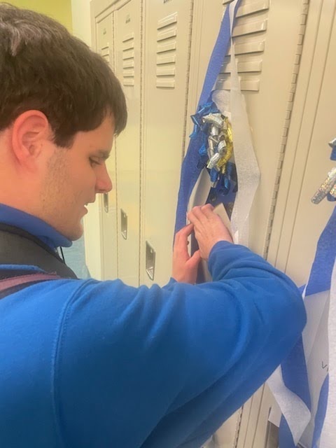 male student smiling as he feels his decorations on his locker 