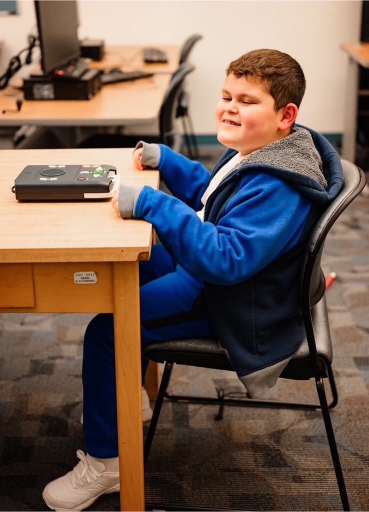 male student wearing a blue track suit sits at a desk