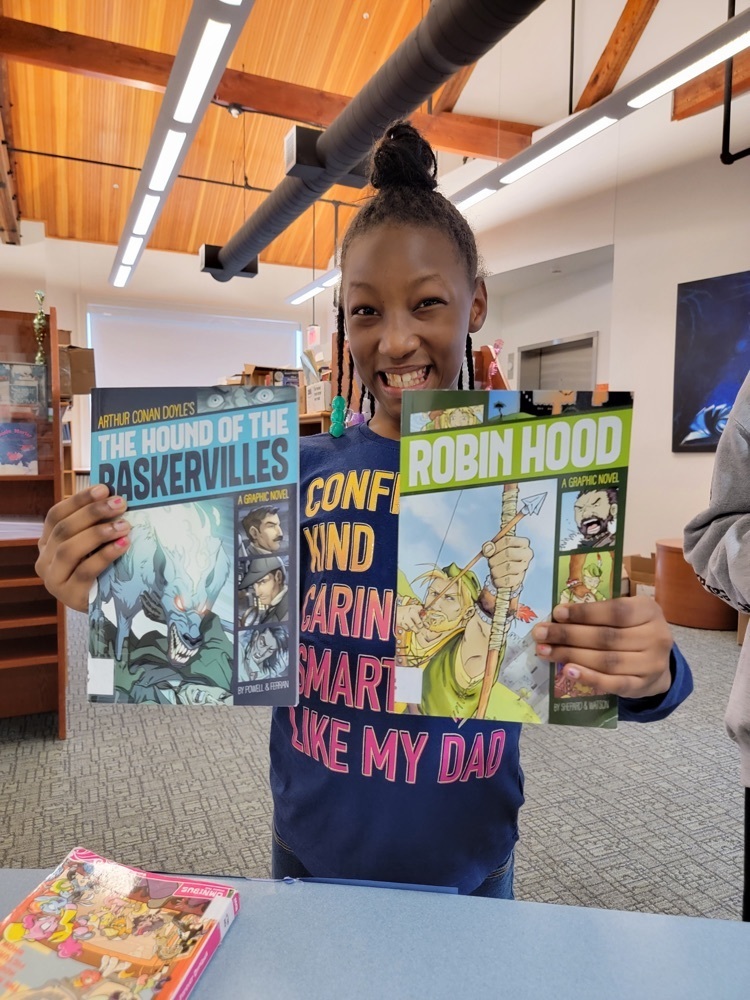 female student holding graphic novel versions of “the hound of the baskervilles” and “Robin Hood”