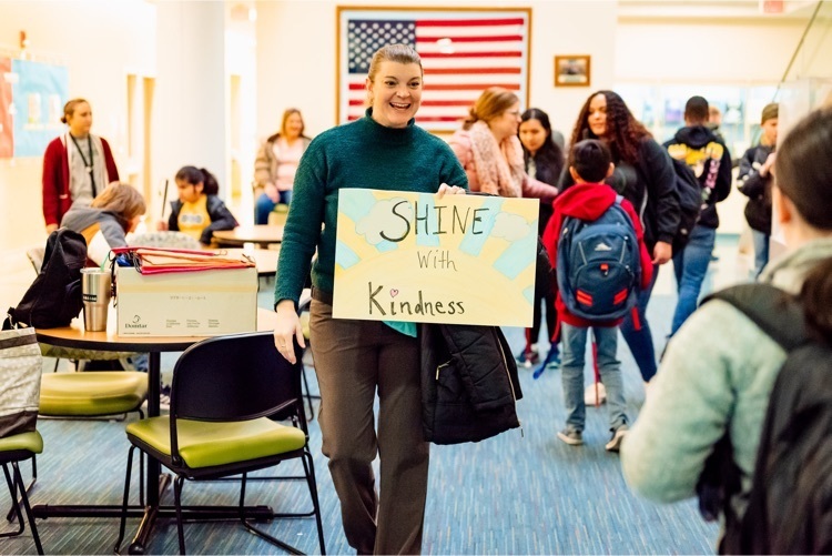 female staff holds a sign that says shine with kindness 