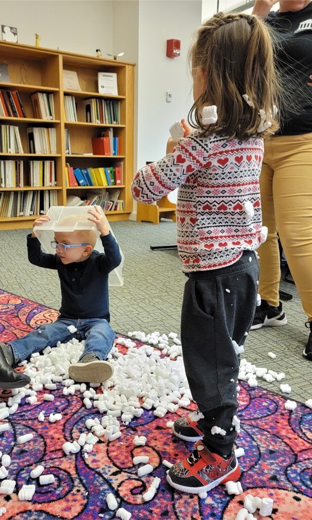 two pre-k students play with packing peanuts in the library 