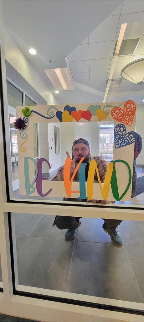 male staff squatting behind a photo frame attached to a window