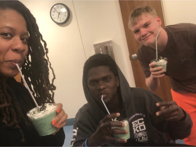 two students smile and drink their shamrock shakes