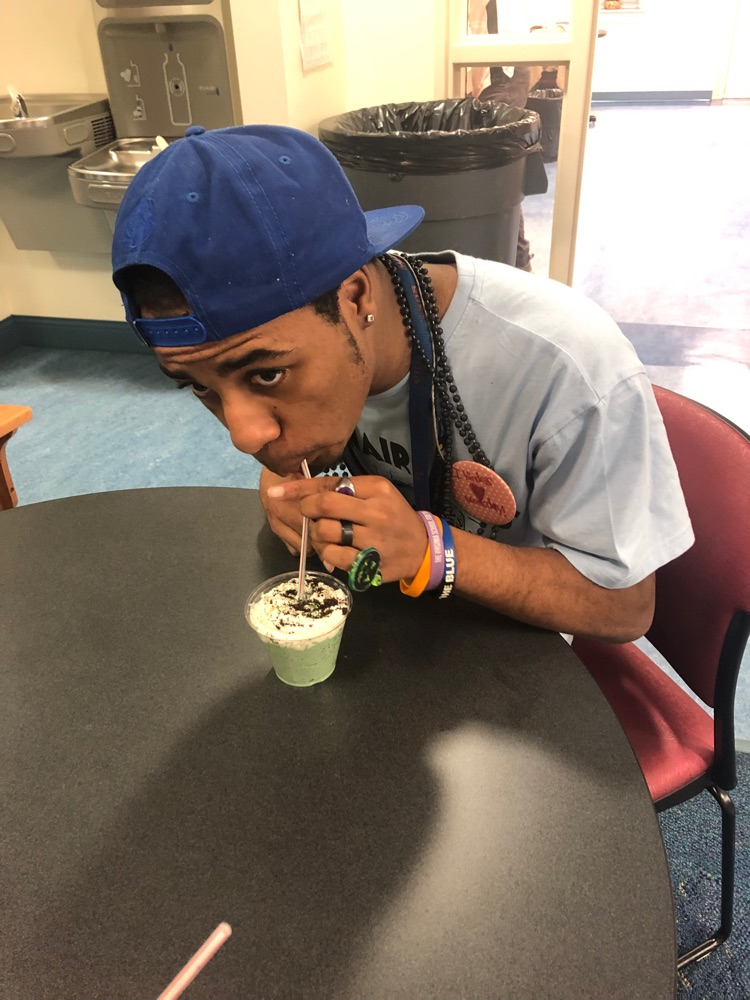 one student leans over the table to drink his shamrock shake