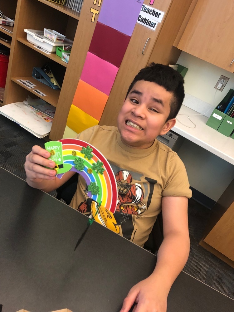 male student holds up his completed rainbow craft 