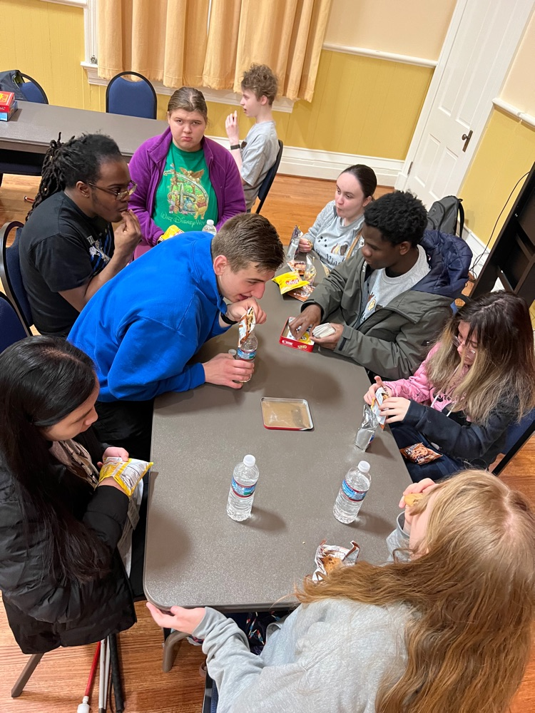students sitting together at a table playing uno