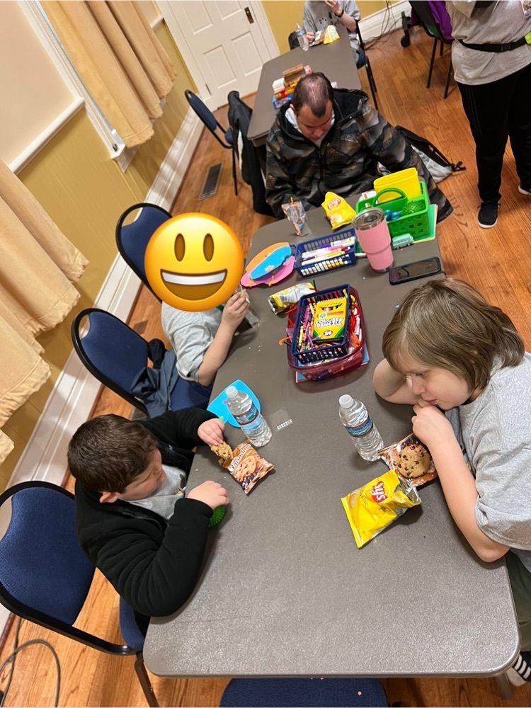 students sitting at a table with crafts and eating snacks 