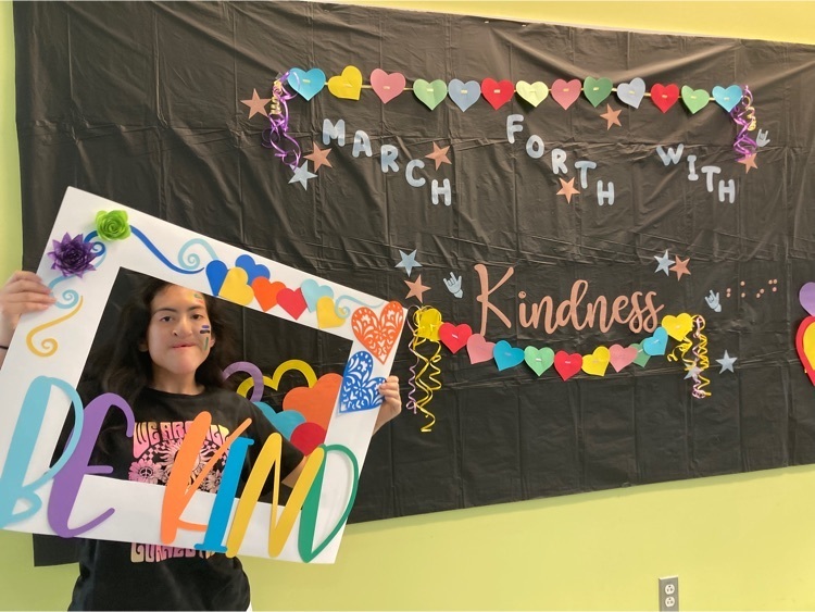 one female student holds up the be kind photo frame 