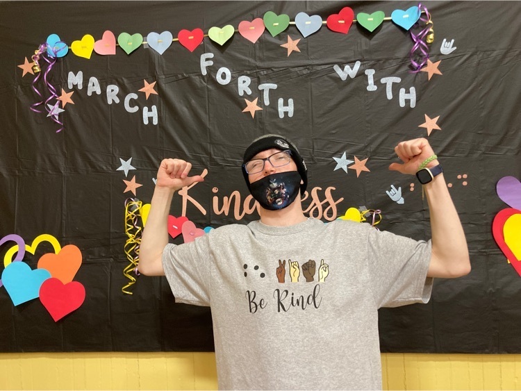 one student poses in front of the kindness week backdrop 
