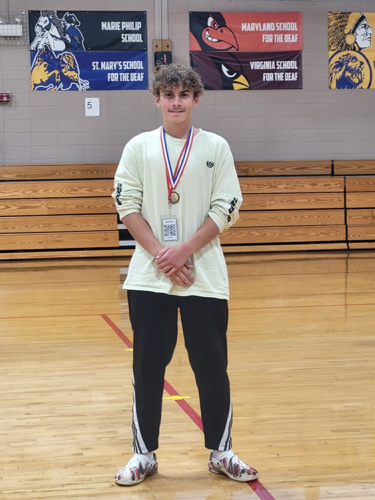 jaxton with an all star medal standing in the gym