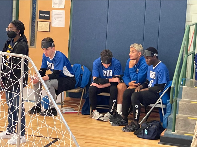 boys and coaches sitting on chairs listening to the game 