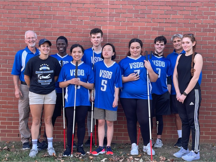 boys and girls teams with coaches standing against a brick wall