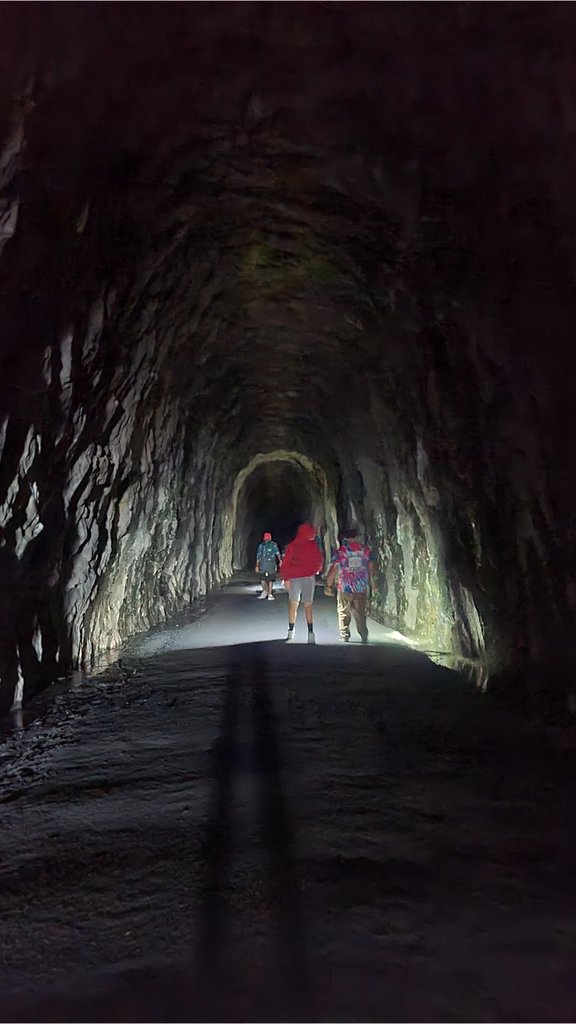 students using flashlights to walk through a long and dark tunnel