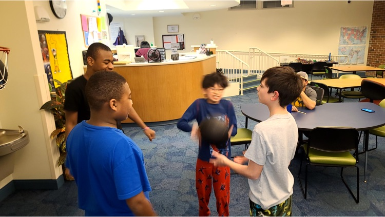 several male students stand in a circle and pass a weighted medicine ball