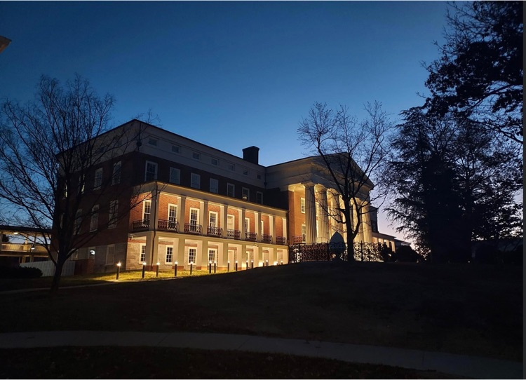 VSDB main hall with exterior lights lit. the photo was taken on the far left side (closest to peery hall) and is angled up and to the right   most of the sky is still dark but the sunshine is starting to peek through from behind the building